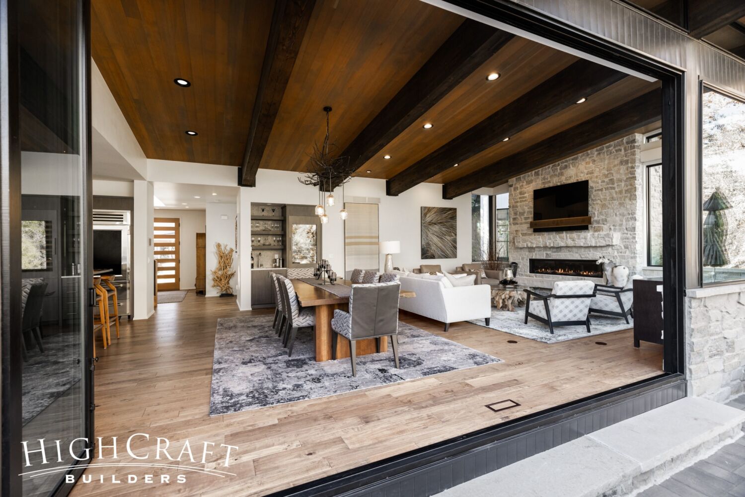 custom-home-builder-Fort-Collins-bifold-door-opening-living-room-ledgestone-fireplace